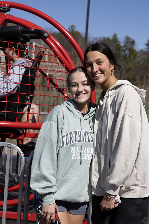 Smiling event attendees at a 2025 NMC Block Party with a ride in the background