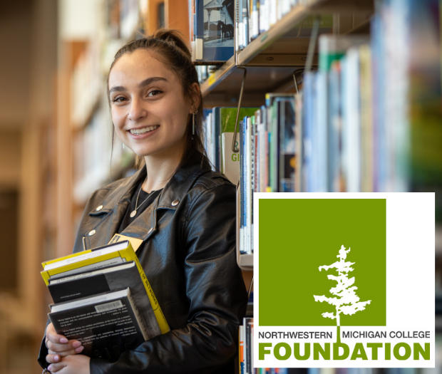 Photo of an NMC student in the library with a stack of books