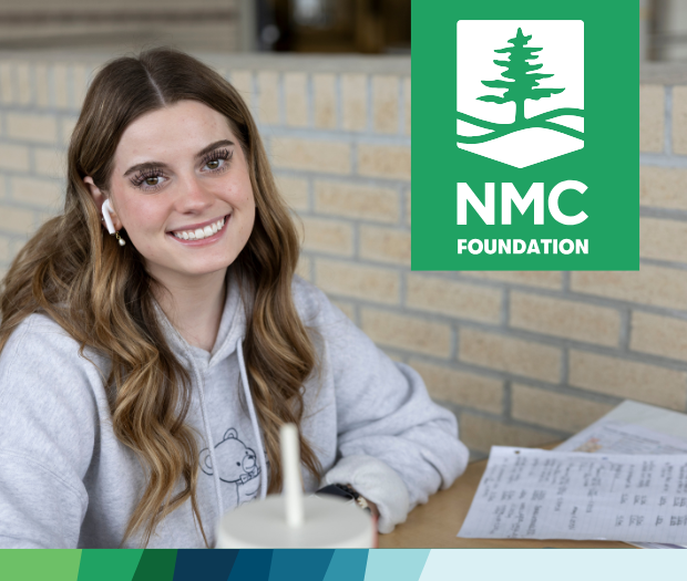 Photo of an NMC student in the library with a stack of books