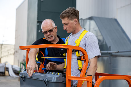 A Construction Technology program instructor operating a lift with a student