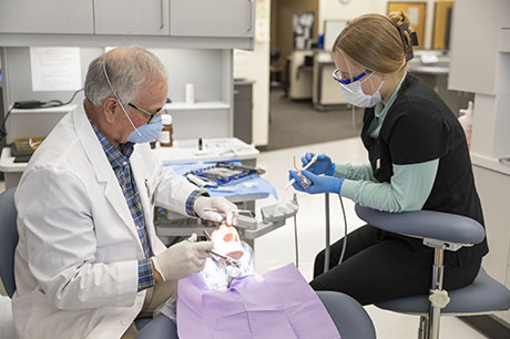 A Dental Assistant program instructor and student work with dental equipment
