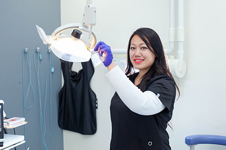 A Dental Assistant program student poses with an exam light