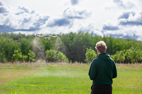 An Uncrewed Aerial Systems (UAS) program student pilots a drone in a field