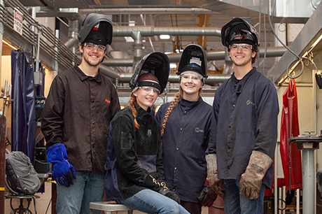 Welding program students pose in a lab 