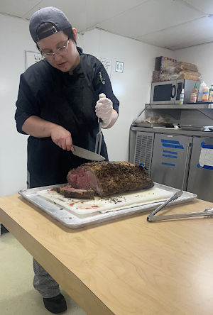 Culinary student Carolyn Fairchild carving meat aboard the Training Ship State of Michigan