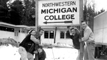 NMC students play in the snow outside a college sign