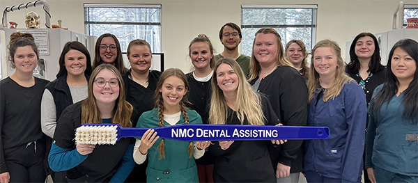 NMC Dental Assisting program students pose with a giant toothbrush