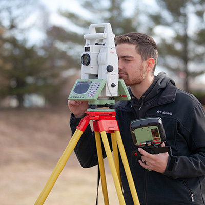 NMC Surveying Technology Program student Gabe Parrish uses a piece of surveying equipment in the field