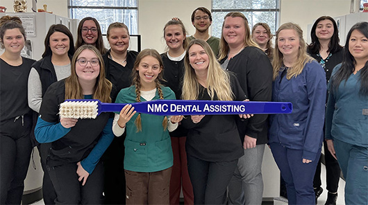 NMC Dental Assistant program students pose with a big toothbrush
