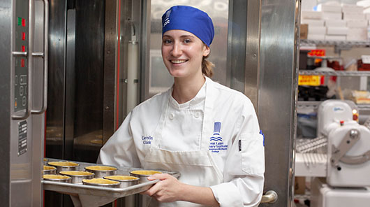 Great Lakes Culinary Institute baking certificate program student Caroline Clark pulls pastry shells from a commercial oven