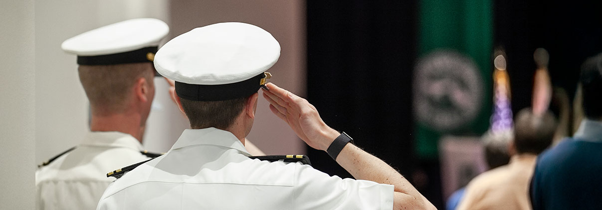 Two men in uniform saluting the flag