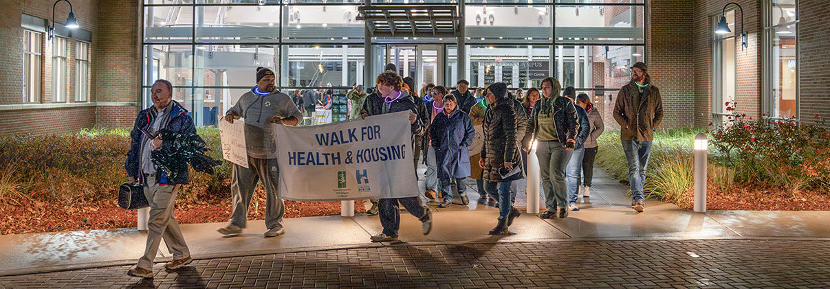 Walkers carry a banner during a Walk for Health and Housing tour of downtown Traverse City from the perspective of people experiencing homelessness and those who serve them.