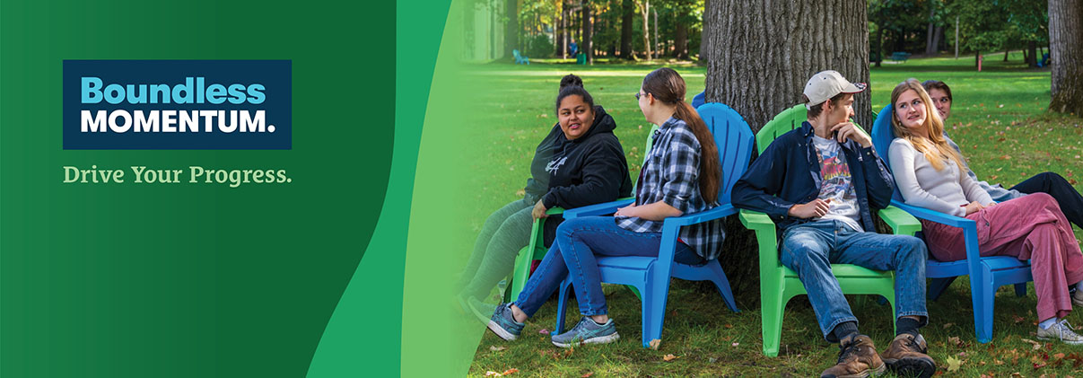 NMC students sitting around a tree under the pines on NMC's Front Street campus