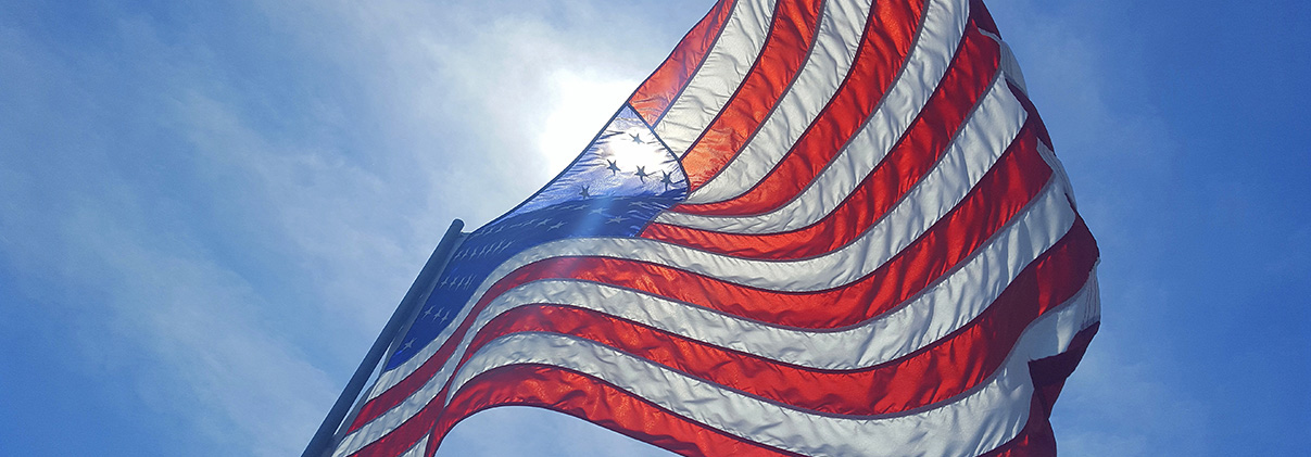U.S. flag with the sun behind it