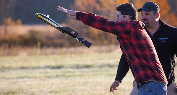 An NMC UAS program student launches a drone while an instructor watches