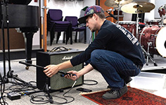 AN NMC Audio Technology Program student wires a piano for sound before a concert