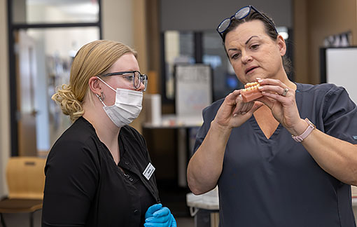 An NMC Dental Assistant Program instructor teaches a dental technique to two students