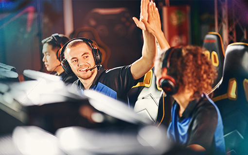 Esports gamers with headphones exchange high-fives during an esports competition