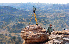 A land surveyor stands atop a rock formation