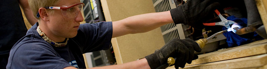 An NMC Construction Technology HVAC Program student repairs an air conditioning unit