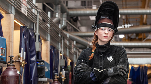 An NMC welding program student in a welder's mask