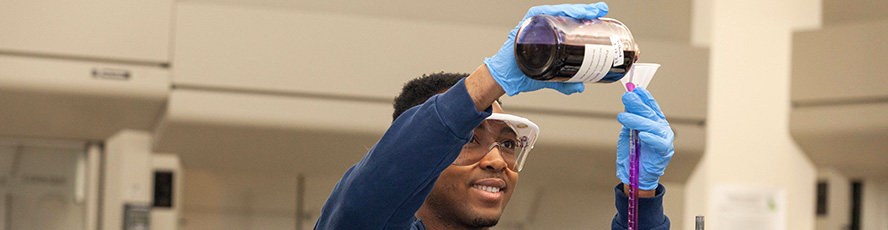 NMC Chemistry program student pouring chemical from a beaker