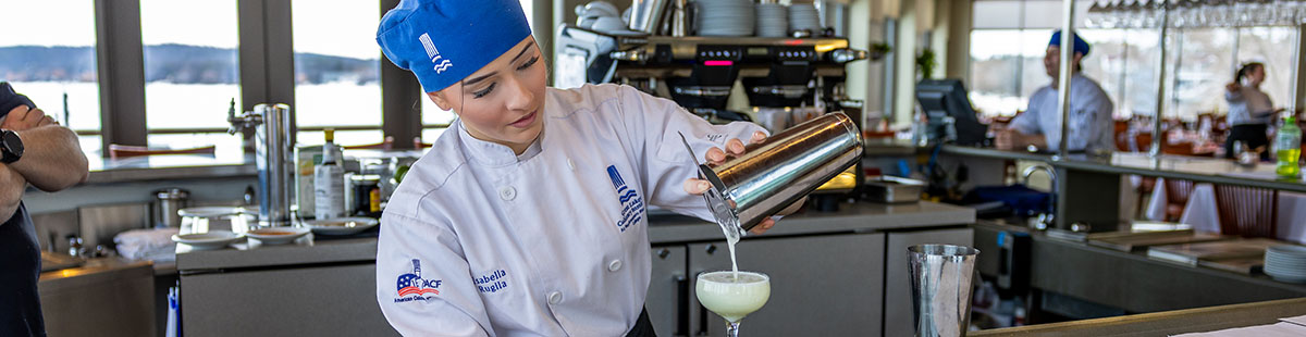 A culinary beverage management program student mixing a drink during a 2026 World Cuisine Night event at Lobdell's Restaurant