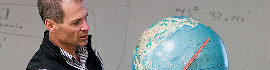 An NMC Geography Program instructor teaches a class and uses a globe of the world in a lesson