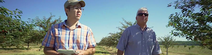 An NMC Plant Science program student and a local farmer inspect a cherry orchard