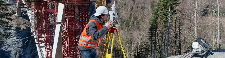 A surveyor using surveying equipment on a bridge construction project