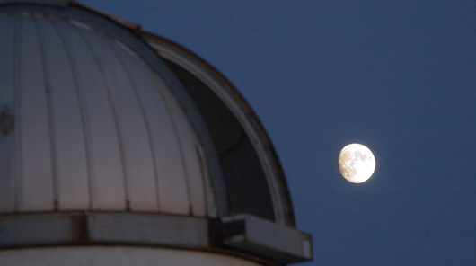 Photo of the observatory at night with the moon in the background