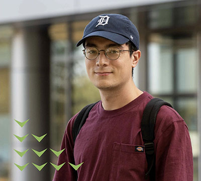 An adult student in a baseball cap stands outside NMC's Timothy J. Nelson Innovation Center