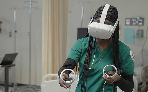 An NMC Nursing program student uses a VR headset and controls during a training exercise.