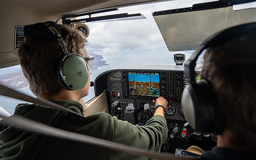 An NMC Aviation program student in the cockpit of a plane over Grand Traverse Bay